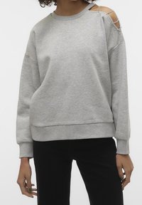 Felpa grigia con vestibilità ampia, polsini a costine e design con spalla scoperta. Tessuto morbido con una texture liscia e dettagli minimi.