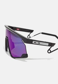 Ochelari de soare sport negri cu lentile violet în degrade, design unghiular și accente din metal. Prezintă un cadru îndrăzneț, tip wraparound, și un logo distinctiv.