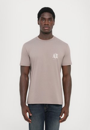 Lys grå bomull T-skjorte med korte ermer, rund halslinning og en liten hvit logo på venstre bryst. Kombinert med mørke jeans.