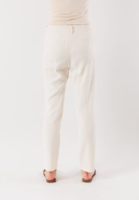 Pantaloni bianchi dal taglio ampio realizzati in tessuto leggero, con vita elastica e design a gamba dritta.