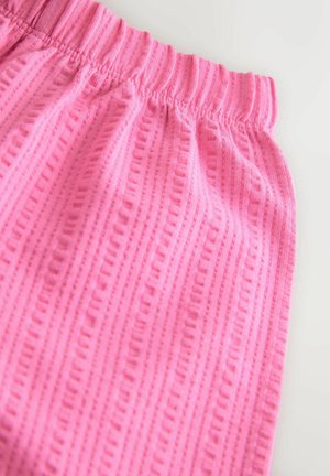 Ružové látkové nohavice s textúrovaným vzorom, s elastickým pásom a vertikálnym pruhovaným dizajnom. Mäkký materiál a pohodlný strih.