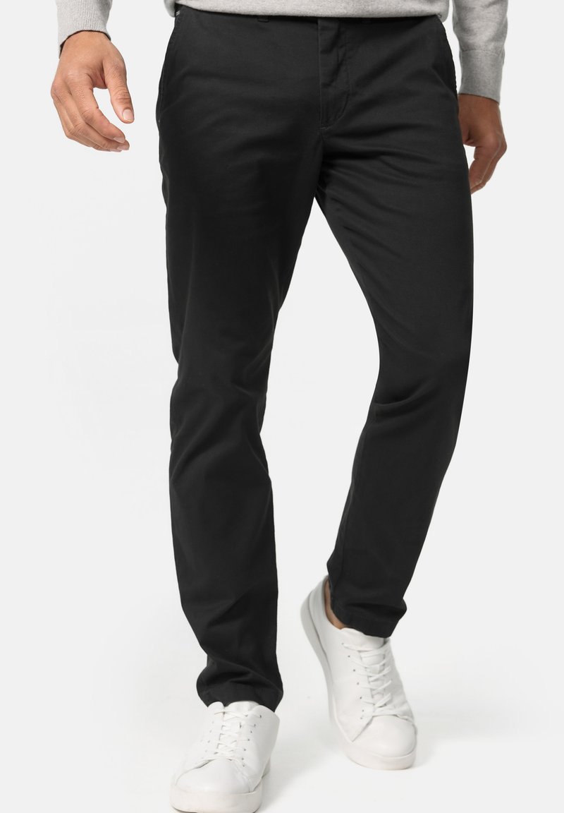 Black trousers with a slim fit, made from a smooth, lightweight fabric. Features a classic design with a zip fly and side pockets.