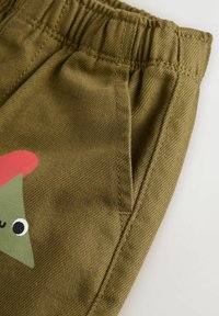 Gyermek olajzöld nadrág texturált felülettel, rugalmas derékszíjjal és nyomtatott mesehőssel az elején.