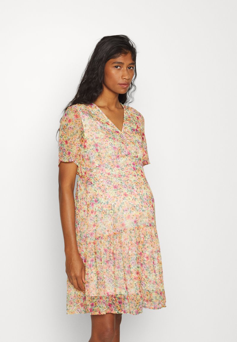 Vestido floral com decote em V e mangas curtas às flutters, apresentando um material leve e suave em cores pastéis e uma saia em camadas com babados.