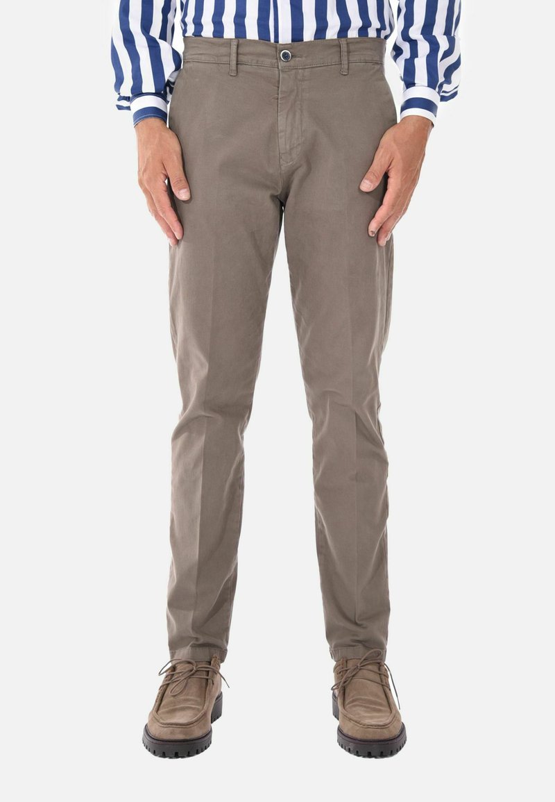 Chinos khaki con vestibilità slim, realizzati in morbido cotone. Presentano pieghe frontali discrete e tasche laterali, abbinati a scarpe marrone chiaro.