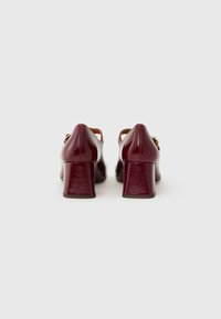 Scarpe con tacco a blocco in pelle lucida bordeaux, con finitura liscia e un design con apertura sul retro, caratterizzate da un dettaglio con cintura alla caviglia.