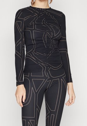 Zwarte top met lange mouwen en een gerimpeld ontwerp, gecombineerd met bijpassende leggings met een vergelijkbaar patroon in contrasterend beige stiksels.