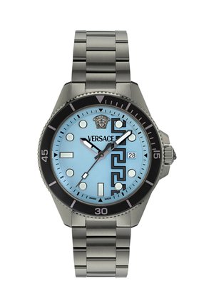 Sølvfarvet metal armbåndsur med lyseblå urskive, sort krans, runde og rektangulære markører, geometrisk mønster, datovisning og Versace-logo.