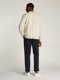 Sweatshirt cinza claro com decote redondo, combinado com calças azul-marinho e ténis brancos. Tecido suave, ajuste descontraído e punhos escutidos.