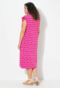 Vestido midi en fucsia con patrón floral blanco, mangas cortas con detalles de lazada y sandalias planas. Tejido suave con un ajuste relajado.