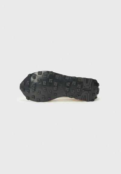 Μαύρη ελαστική σόλα παπουτσιού με υφή που διαθέτει γωνιώδεις προεξοχές και ποικιλία βάθους για καλύτερη πρόσφυση. Λείες άκρες και χωρίς ορατές ενδείξεις.