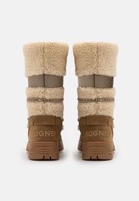 Botas de invierno con forro de piel marrón que presentan una base de ante, una banda elástica con la marca "BOGNER" y suelas de goma texturizadas para mayor tracción.