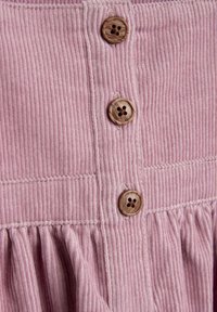 Vestido de pana rosa con ribetes verticales texturizados y tres botones de madera con detalles tallados en forma de flores en la parte delantera. Dobladillo con volantes.
