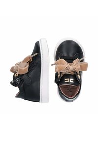Sneakers in pelle nera con suola bianca, arricchiti da un fiocco in velluto beige e dettagli dorati, con una cerniera laterale per facilitarne l'indossabilità.