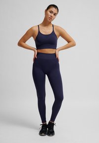 Maritieme sportoutfit bestaande uit een geribbelde crop top met verstelbare bandjes en high-waisted leggings. De stof is glad en aansluitend.