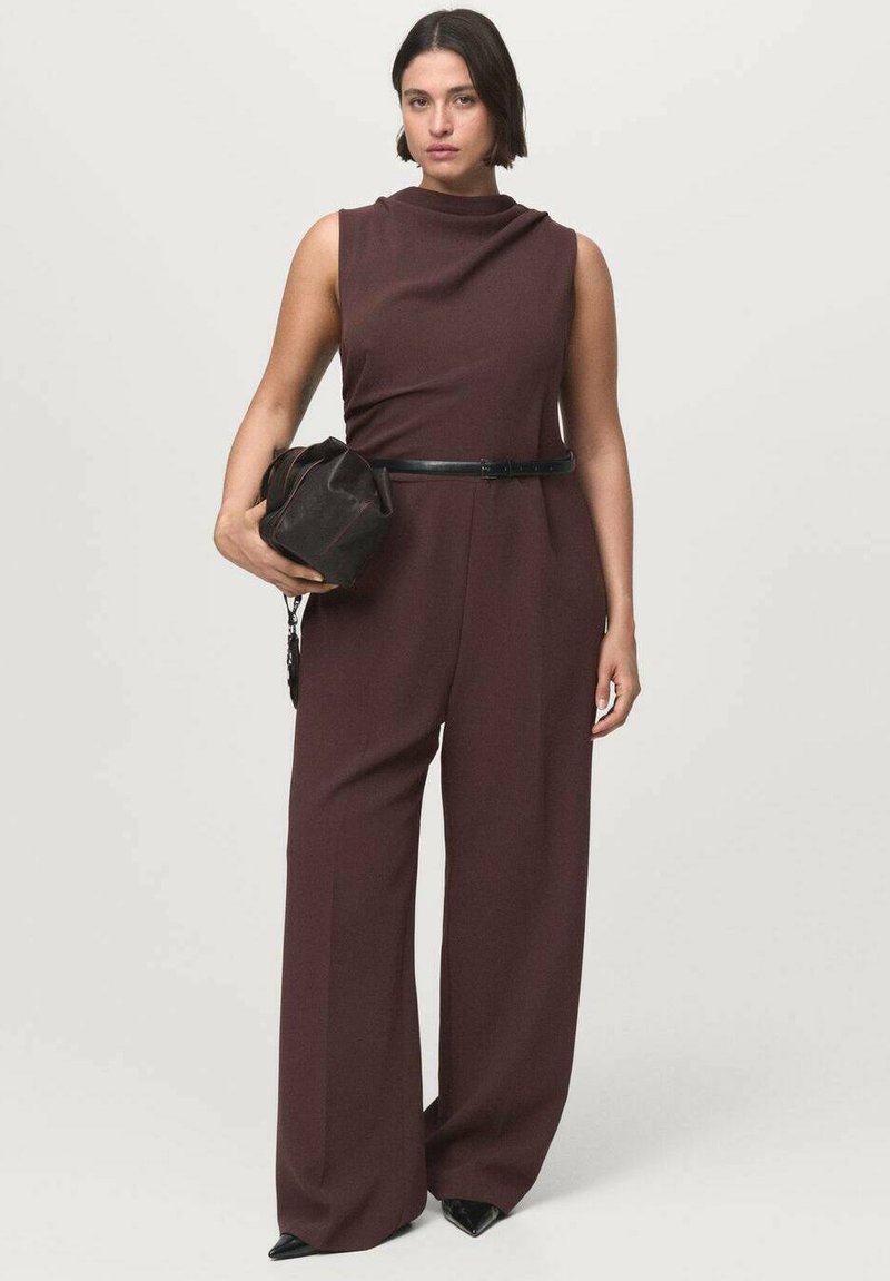 Bordeauxkleurige jumpsuit met een hoge hals, mouwloos ontwerp en wijde benen. Draag met een zwarte riem en een kleine zwarte handtas. Soepele textuur.