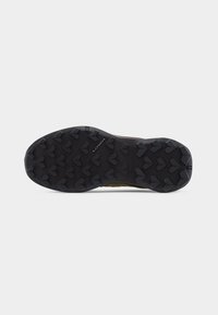 Black rubber outsole of hiking shoe with deep, angular tread pattern and "LOWA" logo at center.