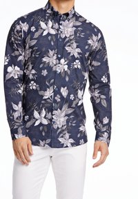 Camicia blu navy con bottoni, caratterizzata da una stampa floreale in tonalità di grigio e bianco, con maniche lunghe e colletto standard. Tessuto dalla texture liscia.
