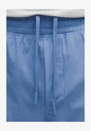 Pantaloni della tuta azzurri con fascia elastica in vita e cordini blu abbinati che pendono sciolti davanti.