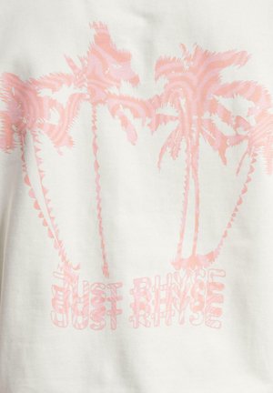 Balta auduma T-krekliņš ar rozā palmu grafiku un tekstu "TIKAI NOSKALOT" rotaļīgā fontā, radot slāņveida efektu.