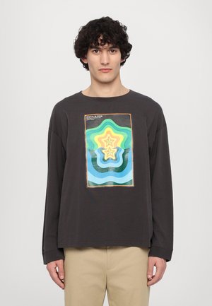 Black long-sleeve t-shirt featuring a colorful graphic of concentric star shapes in green, yellow, and blue. Soft fabric with a relaxed fit.