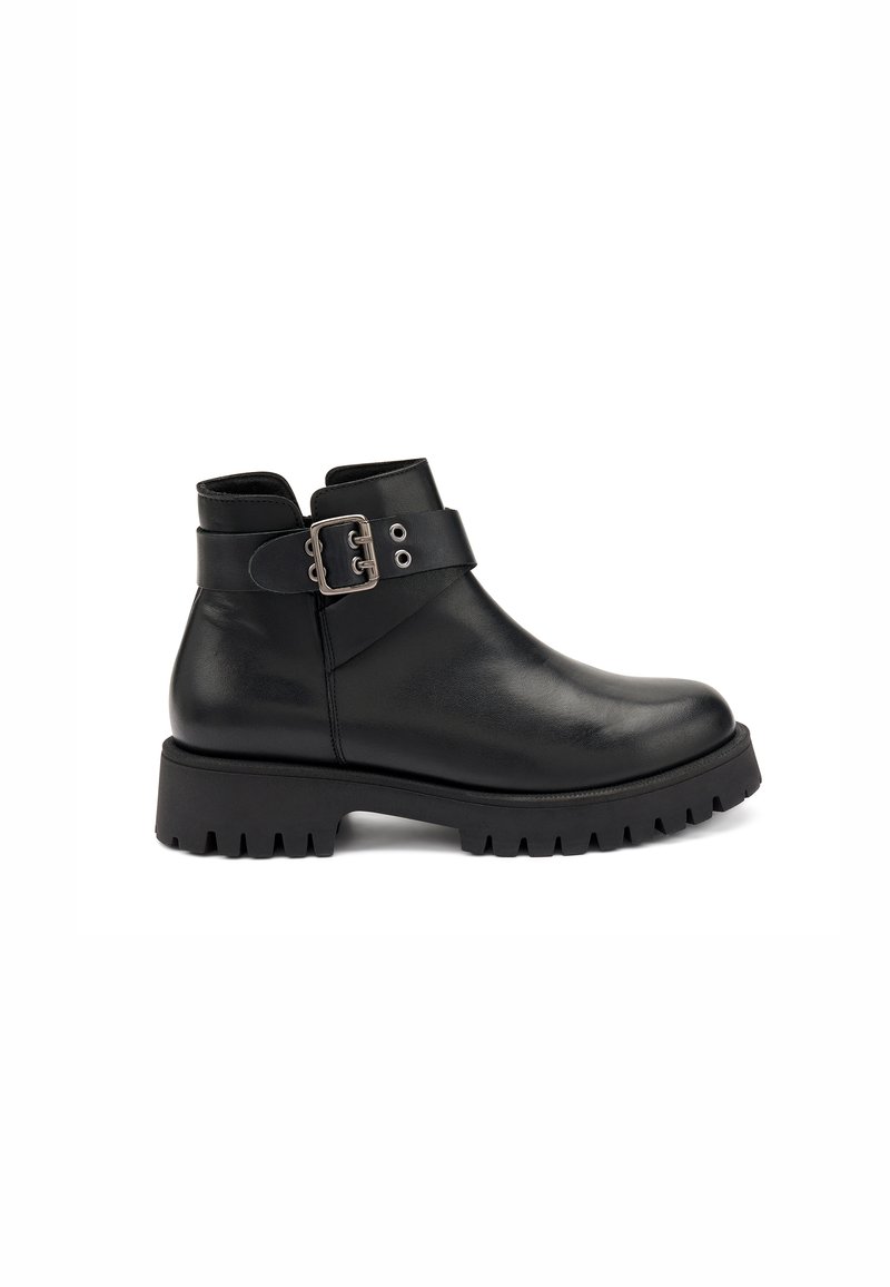 Botas de cuero negro hasta el tobillo con punta redondeada, suela de goma gruesa y una correa decorativa con hebilla. Textura suave sin patrón visible.