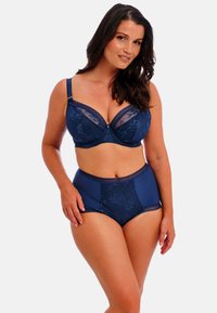 Tummansininen alusvaatesetti, joka sisältää pitsikupillisen rintaliivin ja korkeat alushousut. Molemmissa osissa on kukkakuviota ja läpinäkyviä yksityiskohtia.