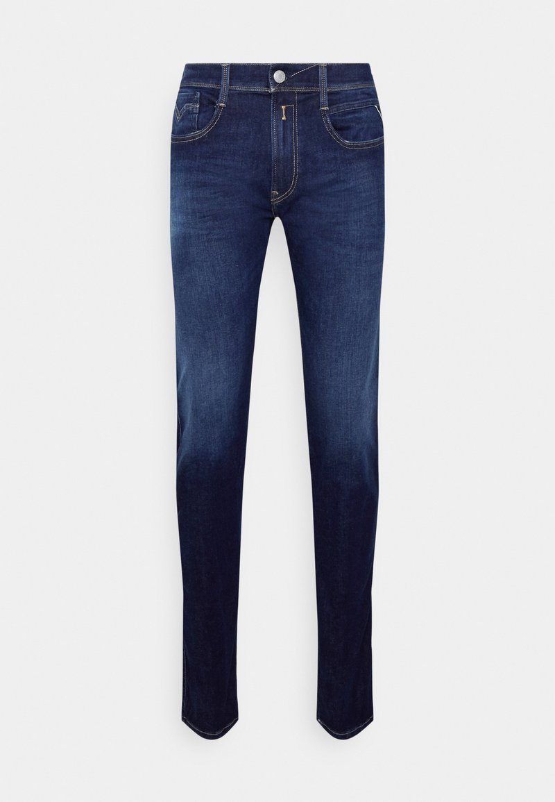 Jeans de mezclilla azul oscuro con un corte ajustado, que presentan un diseño clásico de cinco bolsillos, costuras en dorado y un cierre de botón en la cintura.