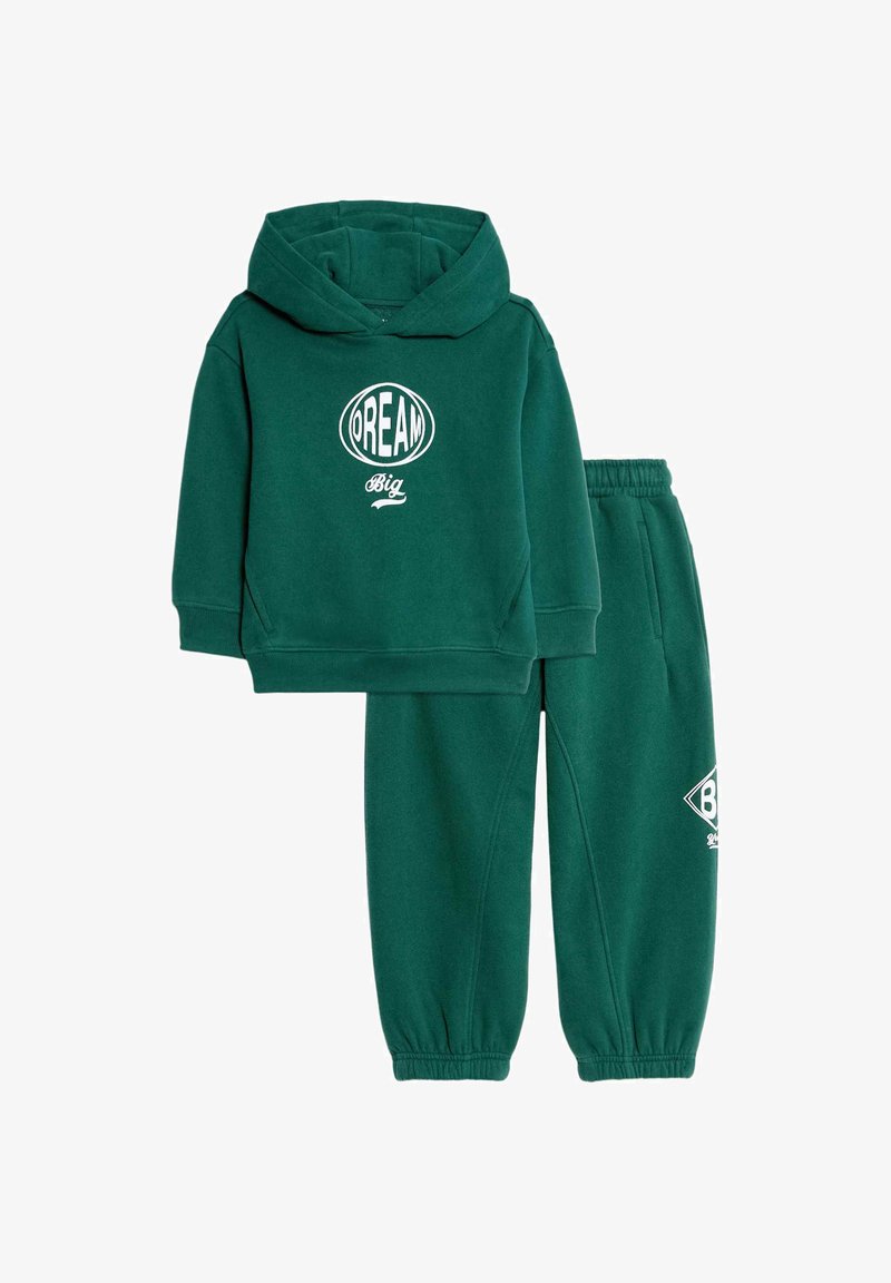 Conjunto de sudadera y pantalones de chándal en verde, con el gráfico "DREAM BIG" en blanco. Material suave, ajuste holgado, puños acanalados y cintura elástica.