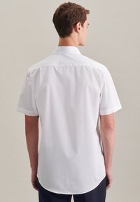 Korte mouwen witte shirt met een puntkraag, gladde katoen stof, een gebogen zoom en opgerolde manchetten. Het achteraanzicht toont een nette, getailleerde pasvorm.