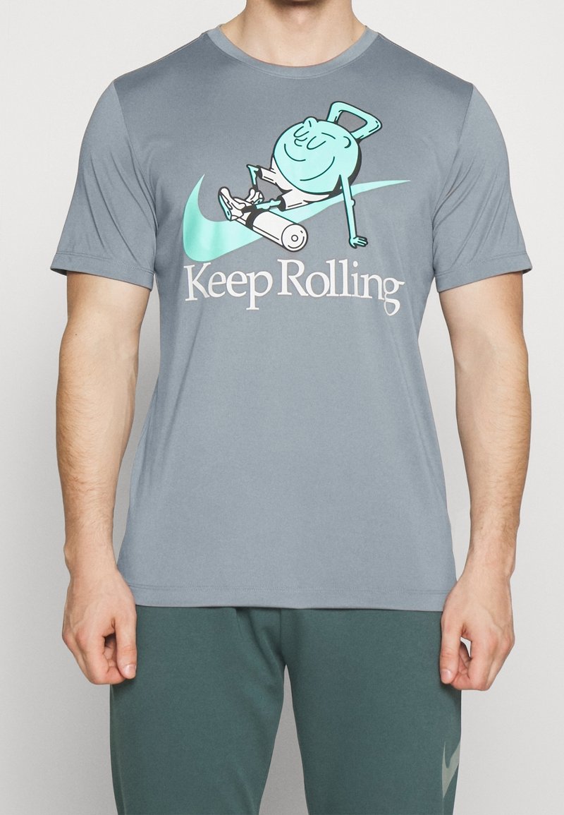 Camiseta gris de manga corta con un personaje de caricatura rodando en un dispositivo con ruedas, con "Keep Rolling" impreso debajo en letras blancas.