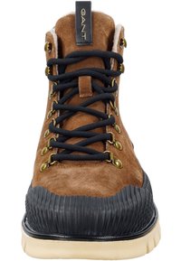 Braune Wildlederstiefel mit schwarzer Gummikappe, ausgestattet mit goldenen Ösen, schwarzen Schnürsenkeln und einer strukturierten Zwischensohle. GANT-Logo auf der Fersenschlaufe.
