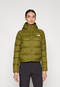 Maslinasto zelena puffer jakna s patentnim zatvaračem sprijeda, pričvršćenim kapuljačom i dva bočna džepa; ima kviltanu teksturu i detalj s logotipom na prsima.