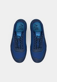 Blue athletic shoes made of synthetic material, featuring a textured upper, flat laces, and a cushioned insole. Accented with lighter blue details.