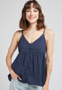 Top sans manches bleu marine en lin, avec un décolleté en V, une fermeture à boutons sur le devant et un design de taille lâche et froncée.