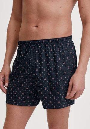 Schwarze, gemusterte Boxershorts mit einem Diamantenmotiv in Rot und Weiß, elastischem Bund und Knopfverschlusdetails, aus leichtem Stoff gefertigt.