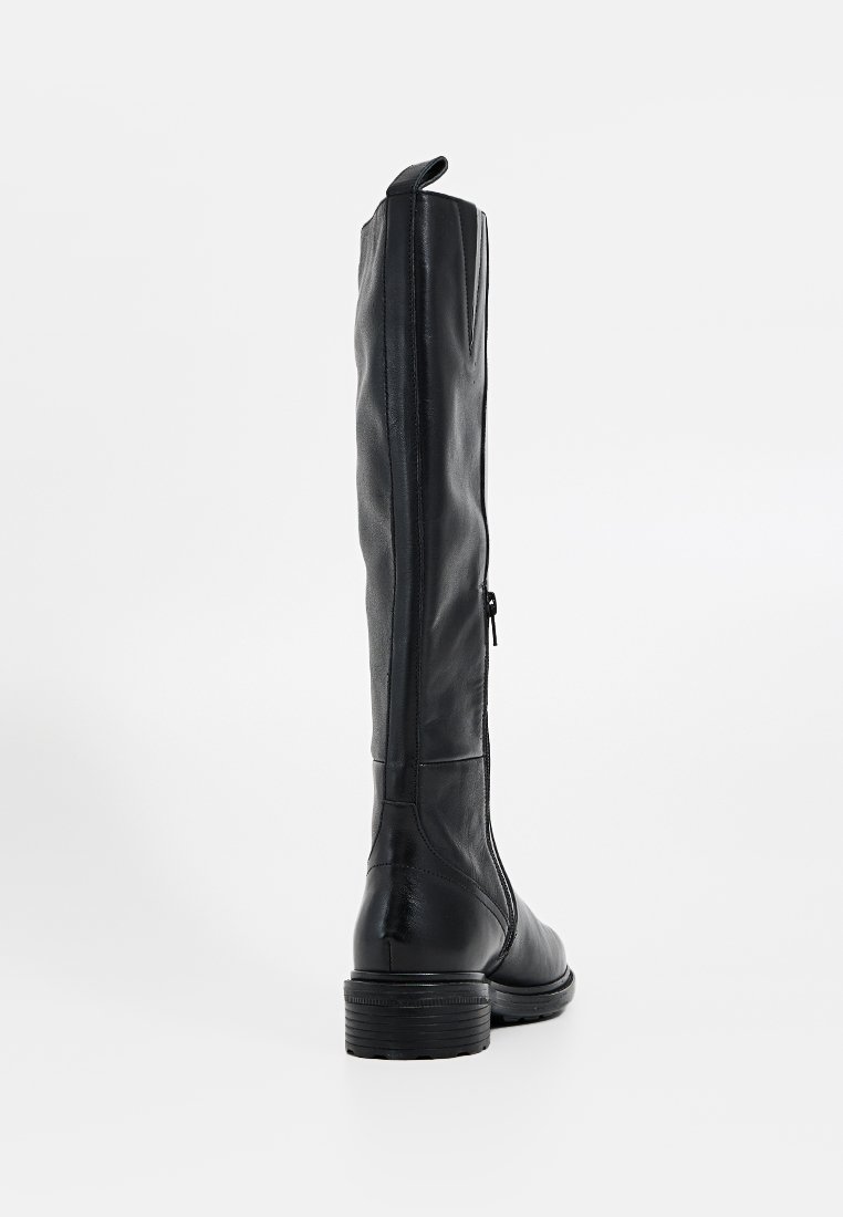 Bota de cuero negro hasta la rodilla con una textura suave, que cuenta con un cierre lateral y un tacón bajo apilado. Líneas limpias y una forma ajustada.