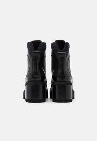 Stivali ankle in pelle verniciata nera con tacco spesso, caratterizzati da una finitura liscia, un inserto posteriore per il pull e dettagli di cucitura sottili.