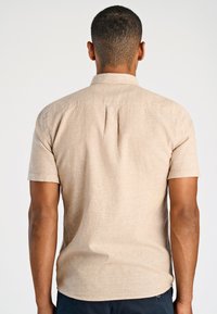 Korte mouwen, beige, linnen overhemd met een button-down kraag en subtiele textuur, met een rechte rugsnit en zonder zichtbare logo's.