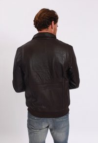 Bruine leren jas met een textuurfinish, een klassieke kraag en geribde manchetten, ontworpen met een schone achterkant en een getailleerd silhouet.