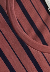 Striped top in reddish-pink fabric with navy stripes. Features a round neckline and a smooth texture. Soft cotton blend material.