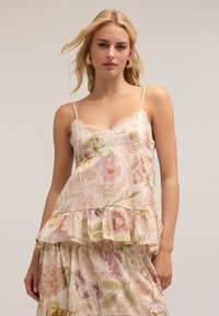 Camiseta floral de tejido ligero, con encaje en los bordes, tirantes finos y un dobladillo con volantes escalonados en suaves tonos de rosa y verde.