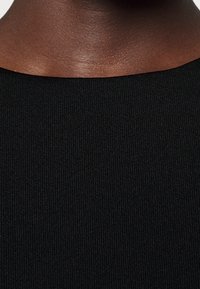 Černá struktura ribového materiálu, detailní pohled, hladký povrch s kulatým výstřihem, zobrazuje jemné vertikální pruhy.