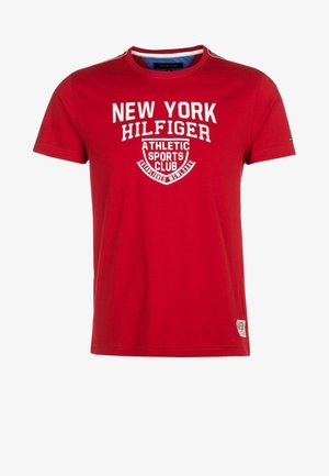 Rotes Baumwoll-T-Shirt mit kurzen Ärmeln, versehen mit weißem Drucktext "NEW YORK HILFIGER ATHLETIC SPORTS CLUB" und einem kleinen Logo auf der Unterseite.