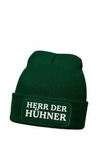 Green beanie hat made of textured knit material with a folded cuff featuring a white patch that displays the text "HERR DER HÜHNERR."