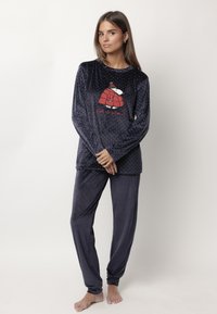 Conjunto de pijama de terciopelo azul marino con puntos, de manga larga y un estampado gráfico de un acogedor iglú con el texto "Que nieve". Textura suave, corte holgado.