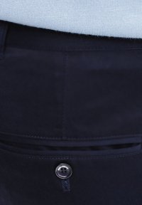 Granatowe materiałowe spodnie z zapięciem na guzik, dwoma tylnymi kieszeniami oraz gładką teksturą z subtelnymi detalami przeszycia.