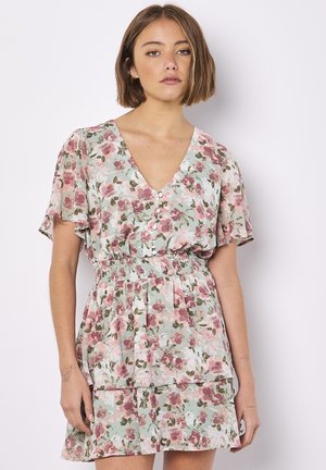 Blumenkleid in Pastellfarben mit V-Ausschnitt, kurzen, schwingenden Ärmeln, gerafftem Bund und mehrlagigem Volant-Saum. Das Muster zeigt rosa und grüne Blumen.