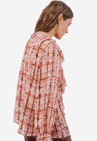 Růžová a hnědá blůza s vzorem, volány, dlouhými rukávy a volným střihem, vyrobená z lehké texturované látky.