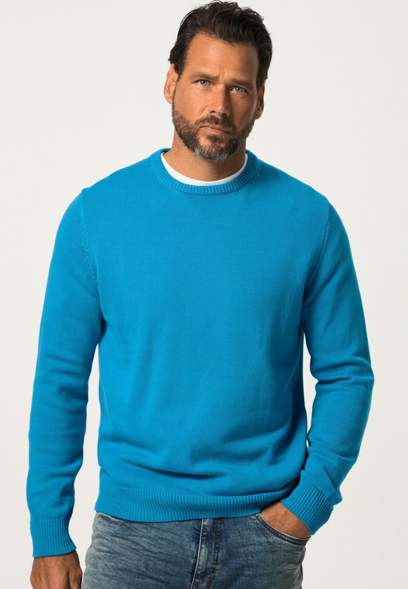 Blauer Baumwollpullover mit Rundhalsausschnitt und gerippten Bündchen, kombiniert mit Jeans. Die Textur ist glatt, in einer einfarbigen, lebendigen Farbe.